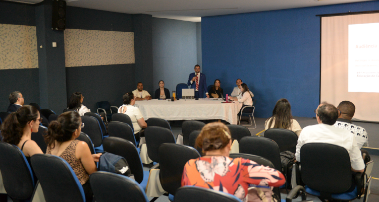 Fotografia de plateia e mesa com participantes da audiência