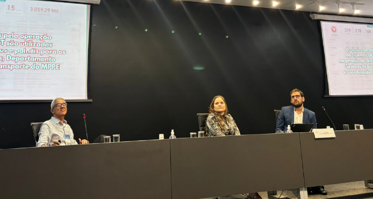 Fotografia de pessoas sentadas na mesa de apresentação do evento